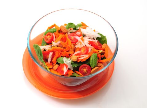 a healthy salad in a clear bowl on an orange plate isolated on white background