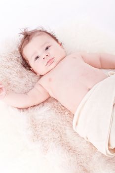 cute little baby infant toddler lying on white blanket smiling portrait