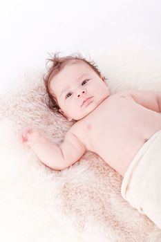 cute little baby infant toddler lying on white blanket smiling portrait