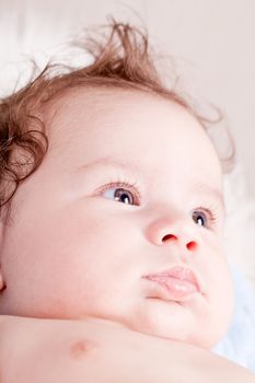 cute little baby infant toddler lying on white blanket smiling portrait