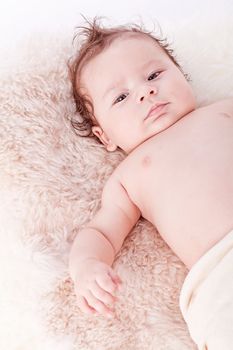 cute little baby infant toddler lying on white blanket smiling portrait