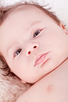 cute little baby infant toddler lying on white blanket smiling portrait
