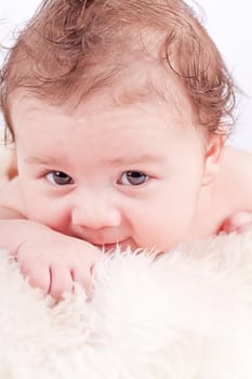 cute little baby infant toddler lying on white blanket smiling portrait