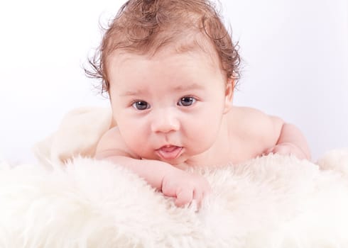 cute little baby infant toddler lying on white blanket smiling portrait