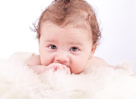 cute little baby infant toddler lying on white blanket smiling portrait