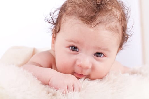 cute little baby infant toddler lying on white blanket smiling portrait