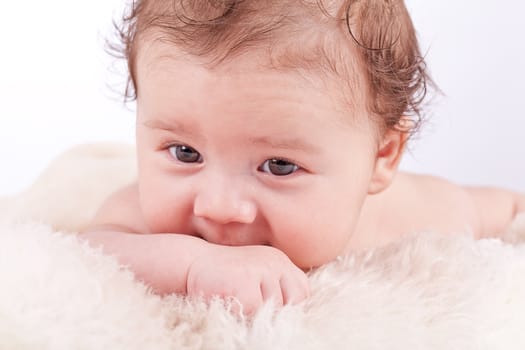 cute little baby infant toddler lying on white blanket smiling portrait
