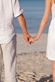 couple in love hand in hand on beach in summer holiday