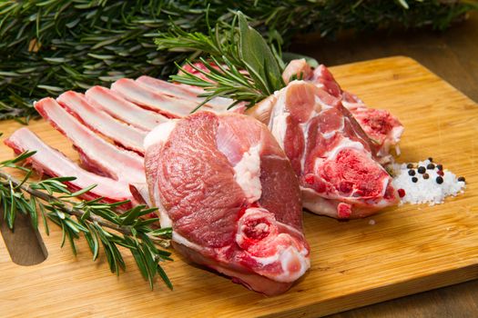 a group of rib lamb with oil and rosemary on wood table