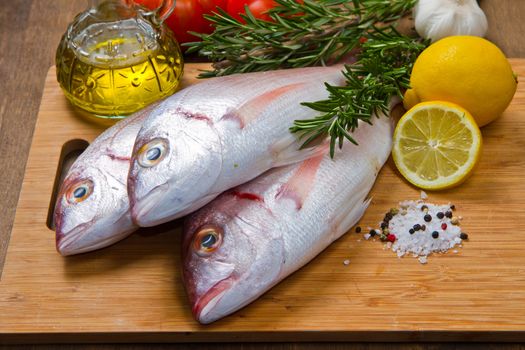 a group of sea bream with lemon and rosemary on wood table