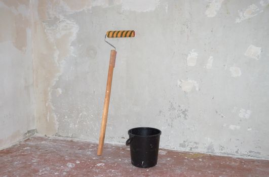 Roller for  putty, bucket  against the background of putty walls
