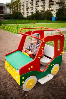 little boy playing on playground in toy car