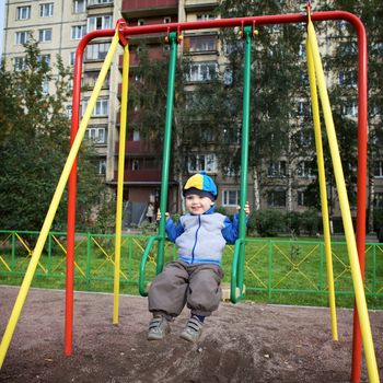 little boy teeter on playground at autumn