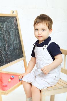little boy drawing with chalk at blackboard
