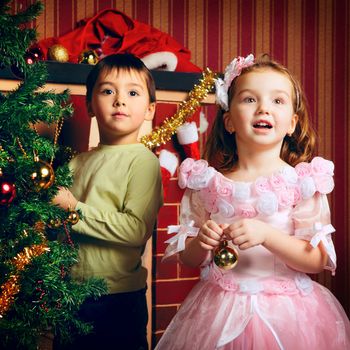 two beautiful happy child decorate christmas tree