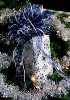 Holiday gift wrapped in snowflake wrapping paper with a blue and silver bow
