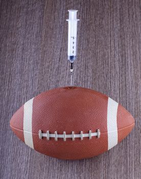A football with a syringe injecting over wooden background