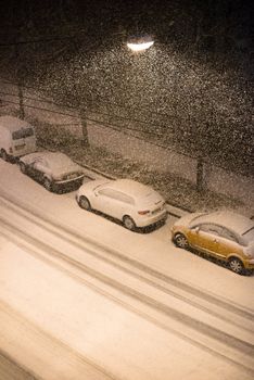 View from above on cars parked along a street at night in heavy winter snow