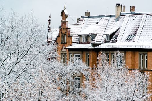 The front of a large older home and trees covered in fresh snow in Stuttgart, Germany