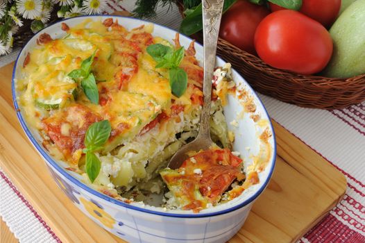 casserole of pasta with zucchini and tomato and cheese on the table