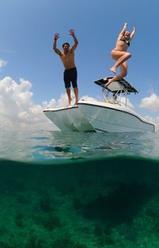 young couple on vacation having fun while jumping off boat