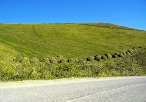 Caucasus autumn landscape. Stacks of dry grass along the road