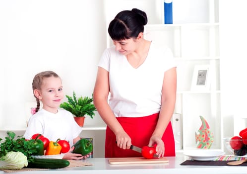 Mother and daughter cooking vegetable salad together