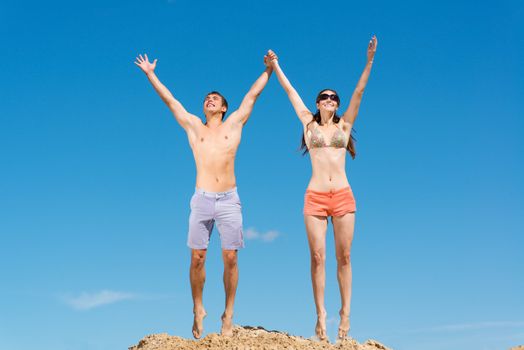 couple jumping together holding hands on a background of blue sky