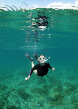 Pretty young woman snorkeling underwater in clear blue ocean