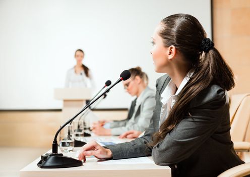 businessmen communicate at the conference, sitting at the table, on the table microphones and documents