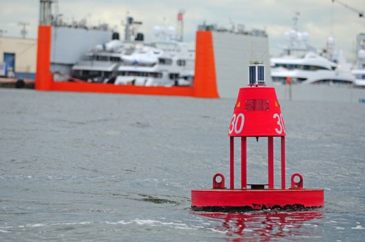 Red buoy that serves as a channel marker near a busy port