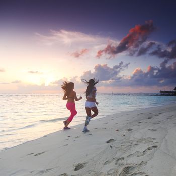 Fitness sport women running on beach at sunset