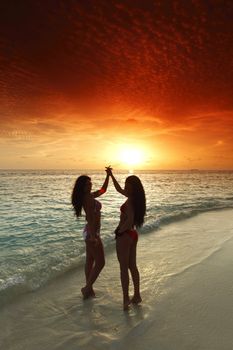 Two beautiful women in bikini enjoying sunset on beach