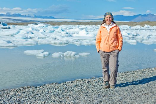 Young woman walking near Jokulsarlon a lake in Iceland where icebergs collapsing from Vatnajokull glacier are floating around.