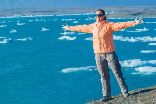 Young woman enjoying the view Jokulsarlon a lake in Iceland where icebergs collapsing from Vatnajokull glacier are floating around.