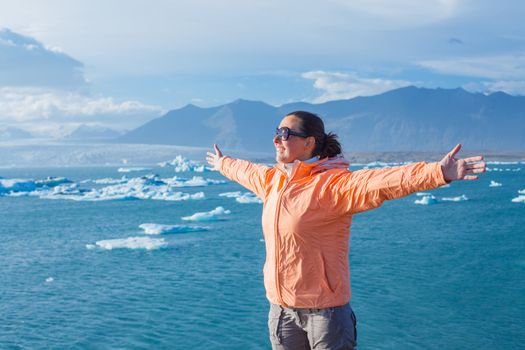 Young woman enjoying the view Jokulsarlon a lake in Iceland where icebergs collapsing from Vatnajokull glacier are floating around.