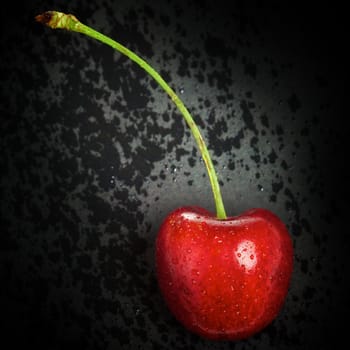 fresh red cherry lying on black background