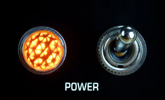 retro guitar amplifier control panel, toggle switch and lamp, close up