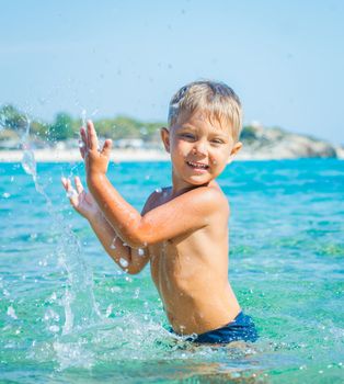 Portrait of young boy swimming and squirting in the transparent sea