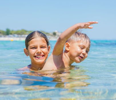 Happy kids. Sister and brother playing and swimming in the transparent sea