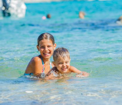 Happy kids. Sister and brother playing and swimming in the transparent sea