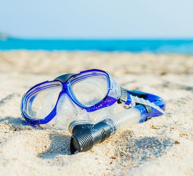 Snorkeling set. Blue diving goggles on sea beach
