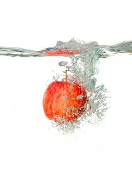 red apple Making a splash while falling into clear water