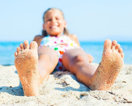 Close-up view of foots by the girl lying on the sand beach.