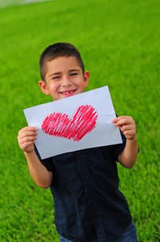 Young boy holding up a gift of a red heart drawing