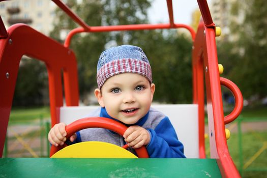 little boy playing on playground in toy car