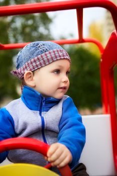 little boy playing on playground in toy car