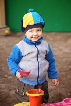 little boy playing in the sandbox at autumn