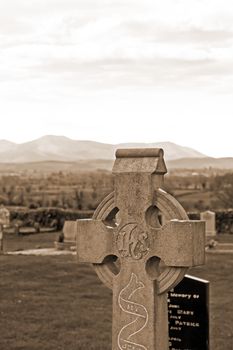 an old celtic cross in an Irish graveyard in sepia