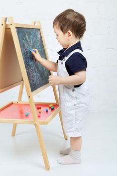 little boy drawing with chalk at blackboard